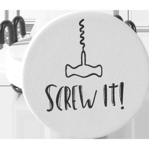May include: A white bottle stopper with a black illustration of a corkscrew and the phrase "SCREW IT!" in a handwritten style. The stopper has a metal wire attachment.