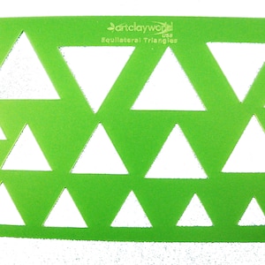 May include: Green plastic stencil with multiple sizes of equilateral triangles cut out. The stencil is labeled "Art Clay World USA Equilateral Triangles".