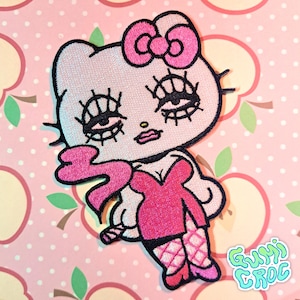 May include: Embroidered patch featuring a stylized cartoon cat with exaggerated eyelashes, wearing a pink dress and bow. The patch has a black outline and the text "GUMI CROC" in a turquoise bubble font.