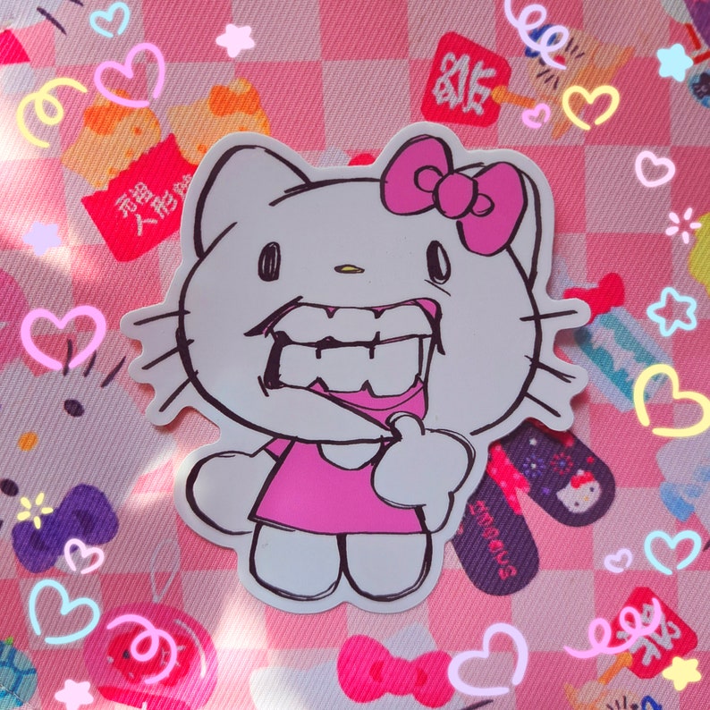 May include: A white sticker featuring a cartoon cat with a pink bow, dress, and a large, toothy grin. The sticker is outlined in black and set against a pink and white checkered background with decorative hearts and stars.