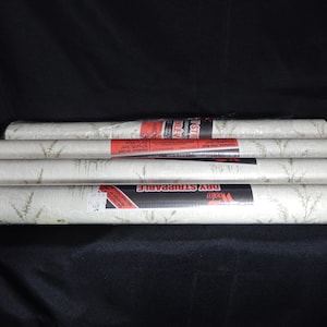 May include: Four rolls of white wallpaper with a subtle pattern of green leaves. The wallpaper is labeled "Dry Strippable" and "Roma".