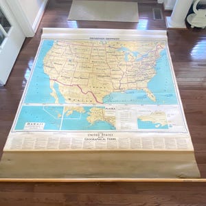 May include: A large, vintage Denoyer-Geppert pull-down wall map of the United States, featuring a tan landmass, blue oceans, and insets for Alaska and Hawaii. The map includes a section titled United States with Geographical Terms at the bottom.