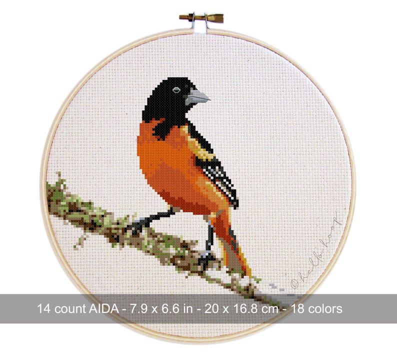May include: Cross-stitch embroidery of an orange and black bird perched on a branch, set in a wooden hoop. The embroidery is 7.9 x 6.6 inches (20 x 16.8 cm) and uses 18 colors. The text reads "14 count AIDA - 7.9 x 6.6 in - 20 x 16.8 cm - 18 colors".