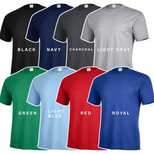 Op de afbeelding: Een verzameling t-shirts met korte mouwen in verschillende kleuren, waaronder zwart, marineblauw, houtskool, lichtgrijs, groen, lichtblauw, rood en koningsblauw. Elk shirt heeft een wit label bij de halslijn, met de kleurnaam in het wit gedrukt.