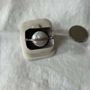 May include: A white ceramic mug with a colorful floral design. The mug features a handle and a wide rim. The flowers are in shades of pink, purple, and yellow. The mug is likely for beverages.