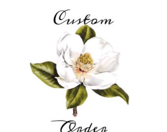 May include: A white magnolia flower with green leaves. The text "Custom Order" is above the flower and the text "Anden" is below the flower.