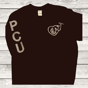 May include: Black long-sleeve t-shirt with gold glitter lettering that reads "PCU" on the left sleeve and a gold glitter heart with a stethoscope and the letters "SLP" inside on the front.