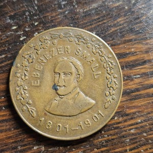 May include: A bronze coin with a portrait of Ebenezer Small and the text "Ebenezer Small 1801-1901" surrounded by a floral design.