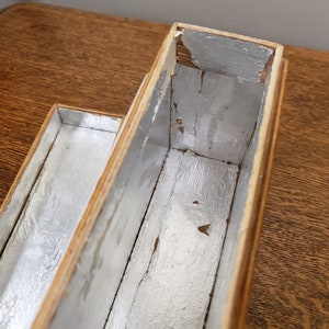 May include: A wooden box with two compartments, each lined with silver foil. The box is made of light wood and has a natural finish.