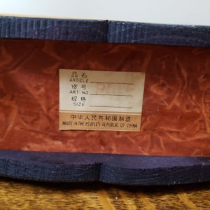 May include: A close-up of a brown wooden box with a black label that reads "品名 ARTICLE ART-NO 规格 SIZE 中华人民共和国制造 MADE IN THE PEOPLE'S REPUBLIC OF CHINA".