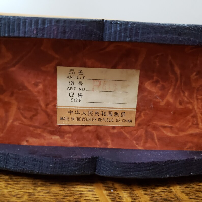 May include: A close-up of a brown wooden box with a black label that reads "品名 ARTICLE ART-NO 规格 SIZE 中华人民共和国制造 MADE IN THE PEOPLE'S REPUBLIC OF CHINA".