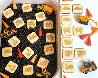 May include: A sensory bin filled with black beans and wooden construction vehicle toys. The bin is surrounded by wooden cutouts of construction vehicles, road signs, and other construction-themed images.