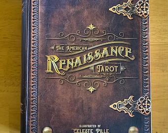 May include: A tarot deck titled "The American Renaissance Tarot" with a brown cover and gold lettering. The cover features decorative gold corner pieces and the names Thea Wirsching and Celeste Pille.