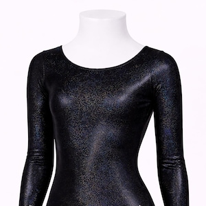 May include: Black long-sleeve leotard with a scoop neckline and a shimmering, iridescent finish. A rhinestone paw print design is on the lower right side. The leotard is displayed on a white mannequin.