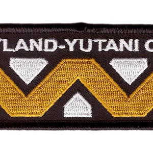 Op de afbeelding: Zwarte geborduurde patch met de tekst "Weyland-Yutani Corp" in wit en een gestileerd "W"-logo in wit en goud.
