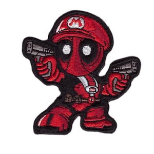 May include: Red and black embroidered patch of a cartoon character wearing a red and white hat with a white 'M' on it, holding two guns. The character has a red and black suit with a white belt and a white stripe on the chest.