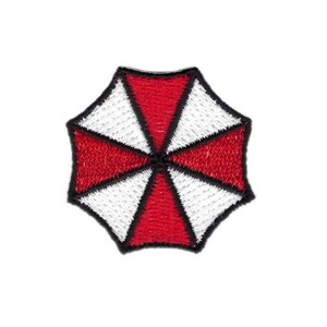 Peut inclure: Patch brodé rouge et blanc avec un contour noir d'un parapluie avec une croix à l'intérieur. Le parapluie est un symbole de la société fictive Umbrella Corporation.