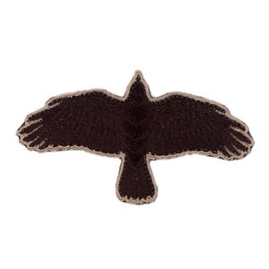 Könnte beinhalten: Ein gestickter Aufnäher eines fliegenden Vogels in Braun mit beigefarbener Umrandung.
