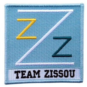 Peut inclure: Écusson brodé avec un fond bleu clair et une bordure blanche. Le motif présente trois lettres "Z" stylisées en jaune, blanc et sarcelle. Le texte "TEAM ZISSOU" est brodé en noir en bas.