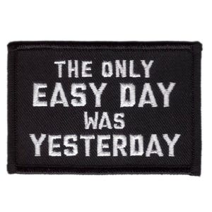 Op de afbeelding: Zwart rechthoekig embleem met witte geborduurde tekst: "THE ONLY EASY DAY WAS YESTERDAY". De patch heeft een zwarte rand en is ontworpen om op kleding of uitrusting te worden genaaid of gestreken.