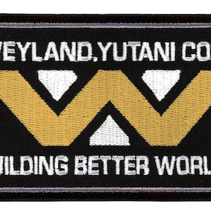 Op de afbeelding: Zwarte en witte geborduurde patch met de tekst "Weyland-Yutani Corp. Building Better Worlds" en een gestileerd gouden "W"-logo.