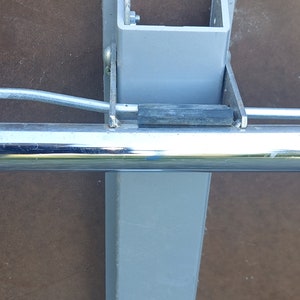 Może przedstawiać: Zbliżenie na szarą metalową nogę stołu z przymocowaną chromowaną belką. Noga ma etykietę z tekstem "Made in China".