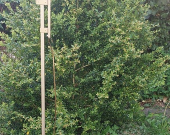 May include: A gold-coloured floor lamp with a curved arm and a round shade. The lamp is standing on a green grassy surface.