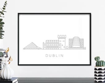 Puede incluir: Impresión enmarcada en negro con un dibujo lineal minimalista del horizonte de Dublín. La obra de arte incluye edificios y estructuras icónicas, con el nombre de la ciudad impreso debajo. La impresión se muestra sobre una superficie oscura.