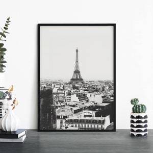 May include: Black and white photograph of the Eiffel Tower in Paris, France. The photo shows the tower from a distance, with the city skyline in the background.