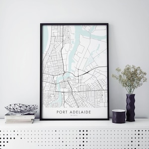 Puede incluir: Una impresión enmarcada en negro de un mapa de Port Adelaide, Australia del Sur. El mapa está en blanco y negro con características de agua azules. El texto "PORT ADELAIDE" y "SA 5015" está impreso debajo del mapa.