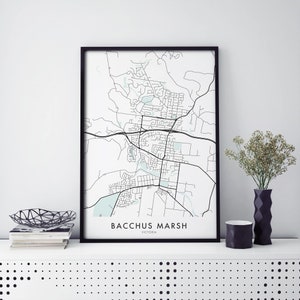 Op de afbeelding: Een zwart ingelijst afdruk van een kaart van Bacchus Marsh, Victoria, Australië. De kaart is in zwart-wit met lichtblauwe accenten. De naam van de stad staat onderaan de kaart gedrukt.