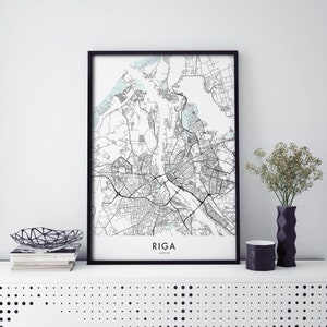 Op de afbeelding: Zwart-witte kaartprint van Riga, Letland, in een zwart frame. De kaart toont de straten en waterwegen van de stad. De naam van de stad en het land zijn onder de kaart afgedrukt.