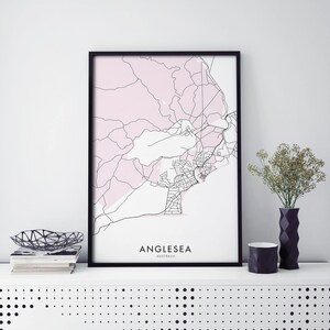 Puede incluir: Una impresión enmarcada en negro de un mapa de Anglesea, Australia. El mapa está en blanco y negro con una superposición rosa. El texto "Anglesea, Australia" está impreso debajo del mapa.