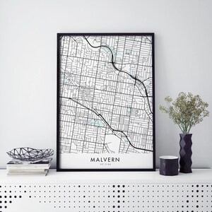 May include: Black and white map print of Malvern, VIC 3144, Australia. The map is framed in a black frame and is displayed on a white shelf with a black and white patterned surface.