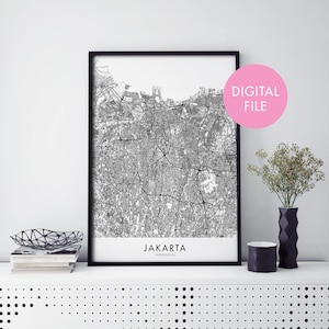 May include: Black and white printable map of Jakarta, Indonesia, with the city name and country printed below the map. The map is framed in a black frame and is displayed on a white shelf with a black and white patterned surface.