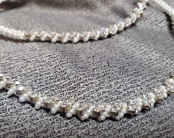 May include: A white headband with a row of small white pearls and clear rhinestones.