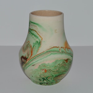May include: A white ceramic vase with a green, brown, and orange marbled design.