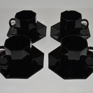 May include: Set of four black octagonal ceramic teacups and saucers. The cups and saucers have a glossy finish.