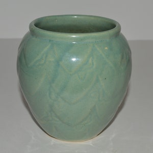 May include: A light green ceramic vase with a textured, leaf-like design.