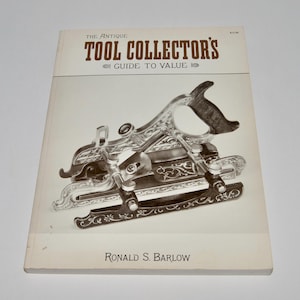 May include: A book titled "The Antique Tool Collector's Guide to Value" with a vintage tool on the cover. The tool is silver and black, with intricate designs. The author's name, Ronald S. Barlow, is printed at the bottom.