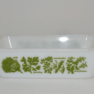 May include: White ceramic loaf pan with green herb illustrations and the words "dill", "parsley", "coriander", and "marjoram" printed on the bottom.