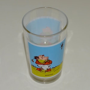 May include: A clear glass with a cartoon illustration of a golfer on a blue background. The text "Birdie" is printed on the bottom of the glass.