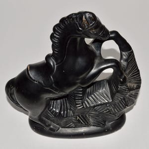 May include: A black horse figurine in a rearing pose, sculpted with detailed features. The horse is set on a textured base, creating a dynamic and artistic display. This decorative piece is suitable for home decor.