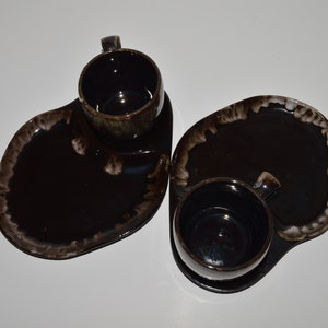 May include: Two brown ceramic coffee cups with matching saucers. The cups and saucers have a mottled brown and white glaze.