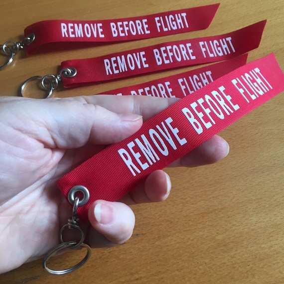 One Remove Before Flight Palm-sized Keyfob. Red Ribbon With White