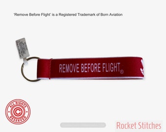 One Remove Before Flight Palm-sized Keyfob. Red stretching webbing with white lettering. airplane/aviation/pilot gift trademarked