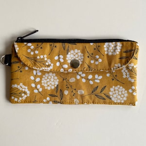 Cartera en efectivo floral mostaza. Bolsillo seguro con cremallera y bolsillo CC. La solapa exterior se cierra a presión. Se adapta a salvaslips.