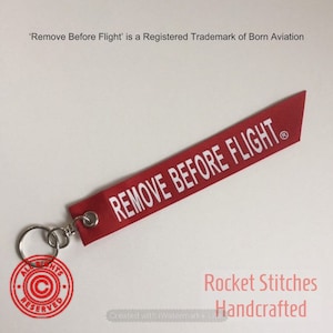 One Remove Before Flight Palm-sized Keyfob. Red ribbon with white lettering. airplane/aviation/pilot gift trademarked