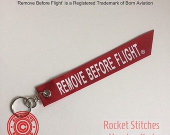 One Remove Before Flight Palm-sized Keyfob. Red ribbon with white lettering. airplane/aviation/pilot gift trademarked