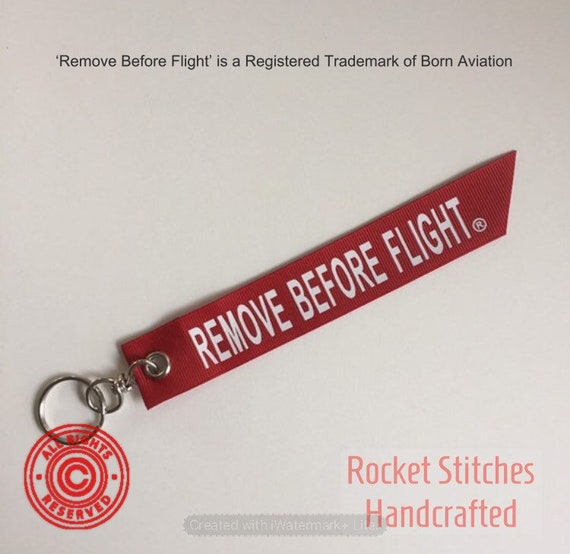 One Remove Before Flight Palm-sized Keyfob. Red Ribbon With White
